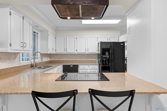 kitchen featuring black appliances, sink, a kitchen bar, kitchen peninsula, and white cabinetry