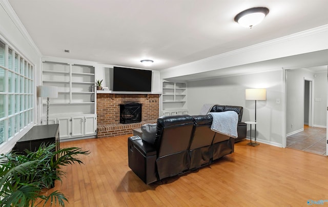 living room featuring built in features, ornamental molding, a brick fireplace, and light wood-type flooring