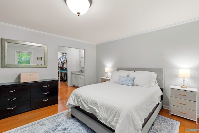 bedroom featuring crown molding, light hardwood / wood-style floors, and ensuite bath