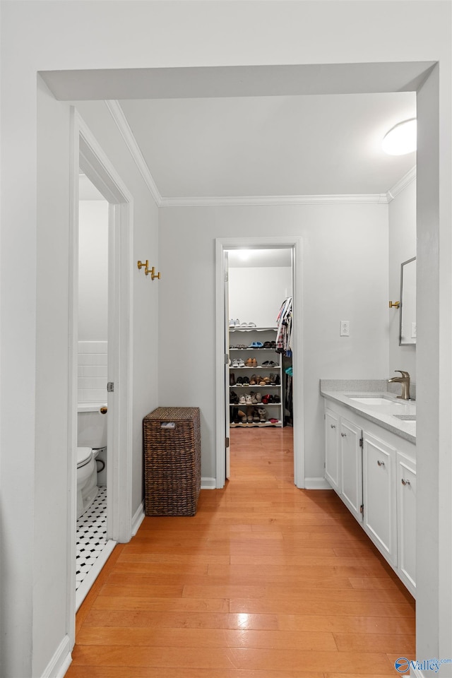 bathroom with toilet, ornamental molding, vanity, and wood-type flooring