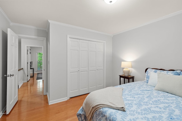 bedroom with a closet, crown molding, and light hardwood / wood-style flooring