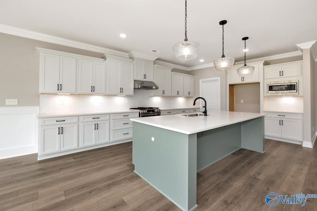 kitchen with sink, appliances with stainless steel finishes, white cabinetry, a center island with sink, and decorative light fixtures