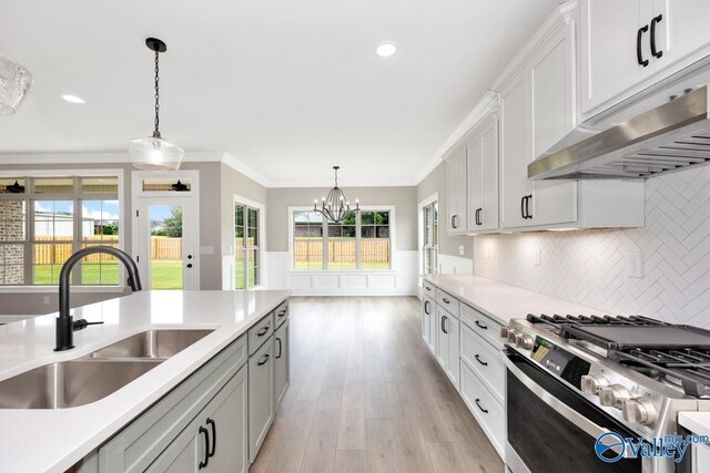 kitchen with decorative light fixtures, white cabinetry, sink, crown molding, and stainless steel range with gas stovetop