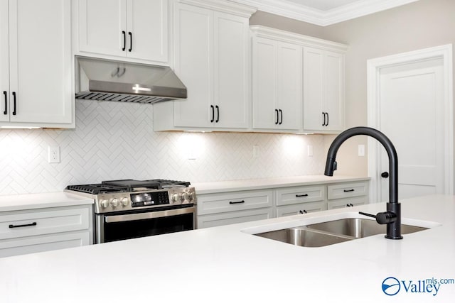 kitchen with wall chimney exhaust hood, sink, stainless steel gas stove, ornamental molding, and white cabinets