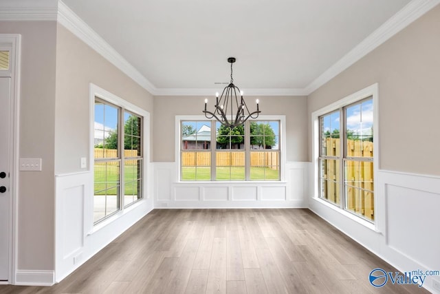 unfurnished dining area featuring hardwood / wood-style floors, a notable chandelier, plenty of natural light, and ornamental molding