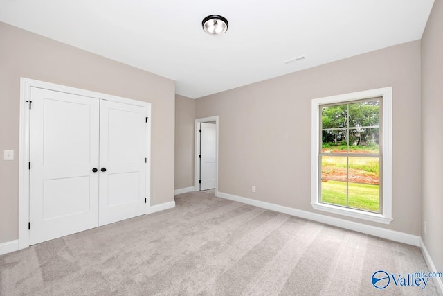 unfurnished bedroom featuring light colored carpet and a closet