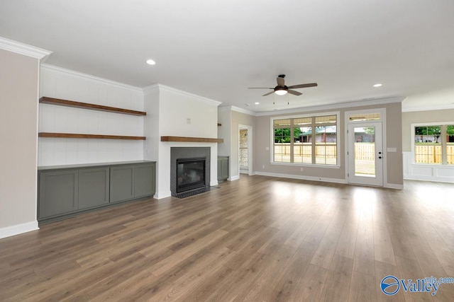 unfurnished living room with ceiling fan, ornamental molding, and wood-type flooring