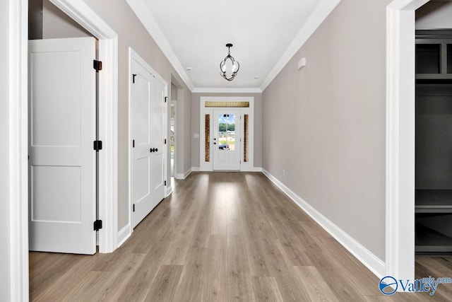 doorway with ornamental molding, a chandelier, and light wood-type flooring