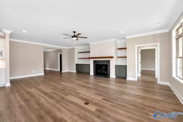 unfurnished living room with hardwood / wood-style floors, ornamental molding, and ceiling fan