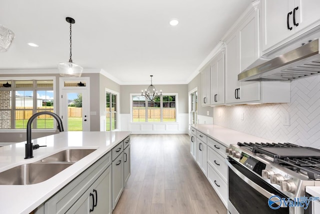 kitchen featuring sink, crown molding, white cabinetry, hanging light fixtures, and stainless steel range with gas stovetop