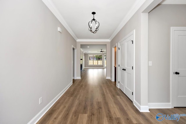 corridor featuring crown molding, hardwood / wood-style flooring, and a chandelier