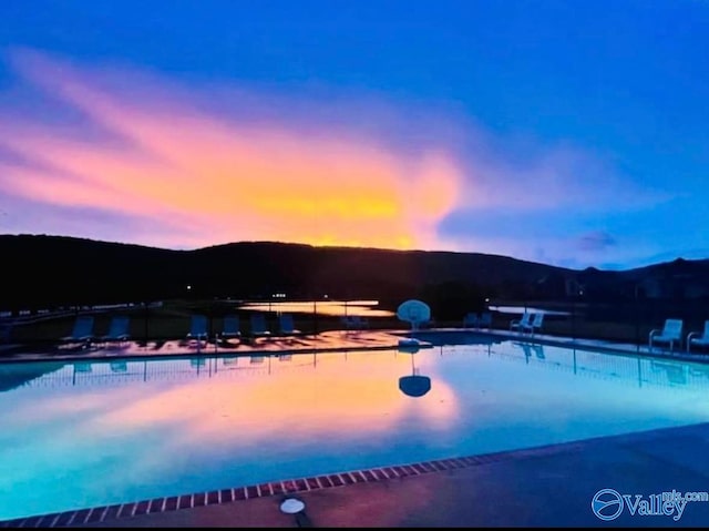 pool at dusk with a mountain view and a patio area