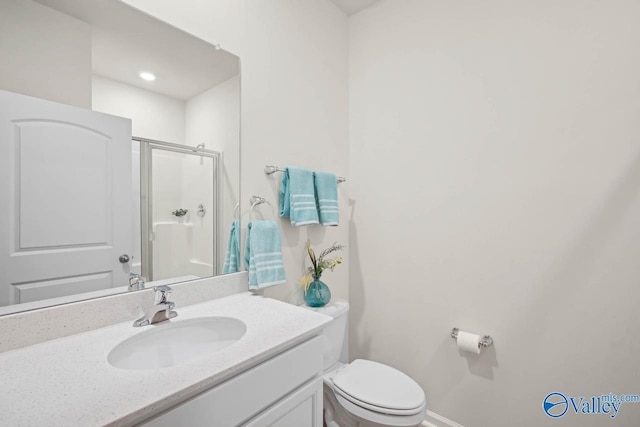 bathroom featuring vanity, a shower with door, and toilet