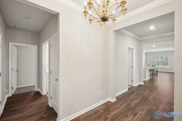 corridor with crown molding, dark hardwood / wood-style floors, and an inviting chandelier