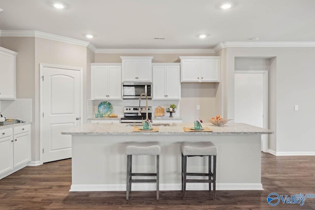 kitchen featuring a kitchen island with sink, stainless steel appliances, dark hardwood / wood-style floors, light stone countertops, and white cabinets