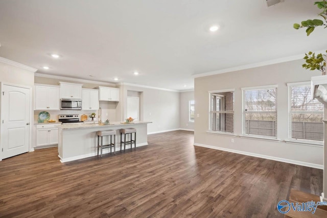 kitchen featuring stainless steel appliances, a wealth of natural light, a center island with sink, and white cabinets