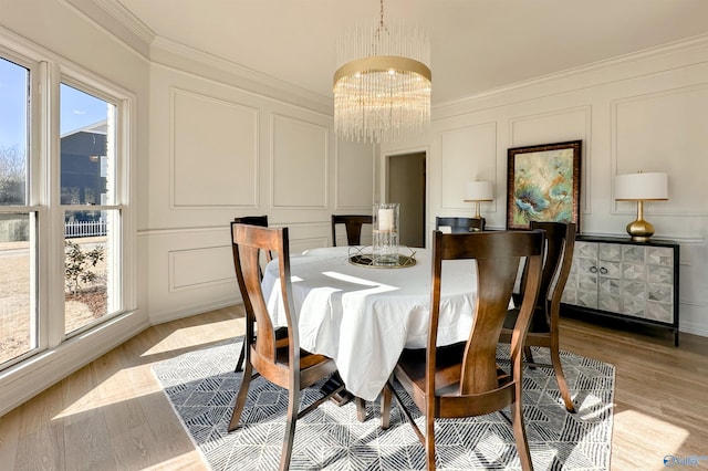dining area with ornamental molding, light hardwood / wood-style flooring, and a notable chandelier