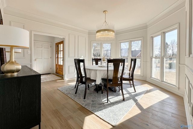 dining space featuring ornamental molding, a notable chandelier, and light hardwood / wood-style flooring