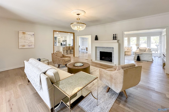 living room with an inviting chandelier, light hardwood / wood-style flooring, and ornamental molding