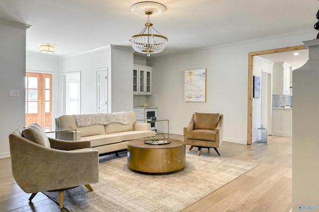 living room with crown molding, a chandelier, and light wood-type flooring