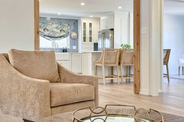 living room featuring crown molding, sink, and light hardwood / wood-style floors