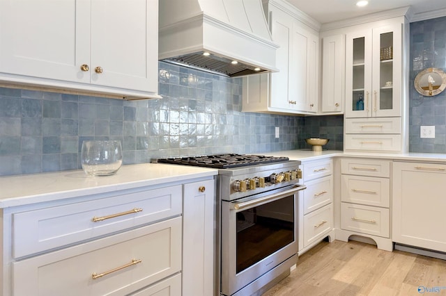 kitchen featuring premium range hood, white cabinetry, tasteful backsplash, high end range, and dishwasher