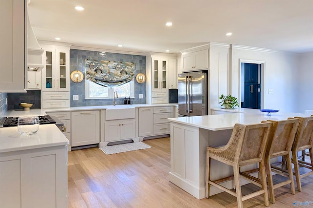 kitchen featuring high end fridge, sink, tasteful backsplash, and white cabinets