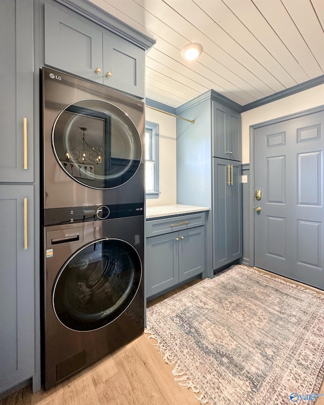 laundry area featuring wood ceiling, cabinets, light hardwood / wood-style flooring, ornamental molding, and stacked washing maching and dryer