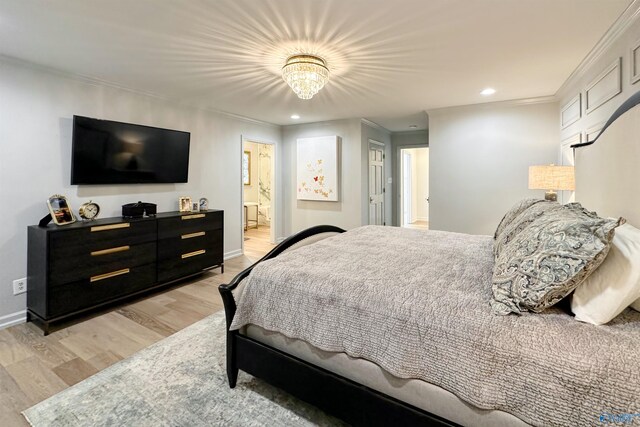 bedroom with crown molding, light wood-type flooring, and ensuite bath