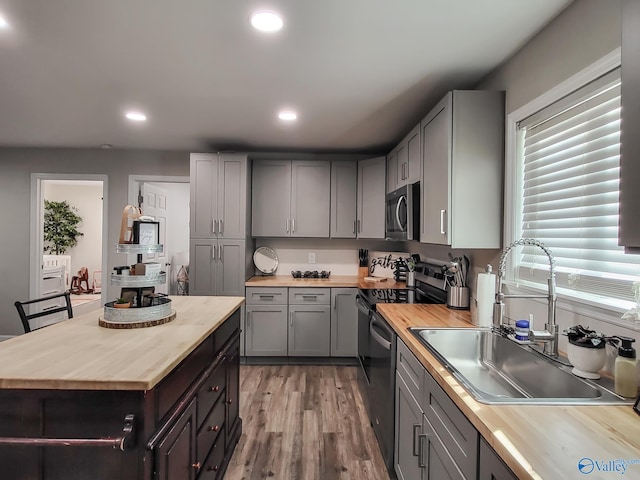 kitchen featuring gray cabinets, wood-type flooring, sink, appliances with stainless steel finishes, and wood counters