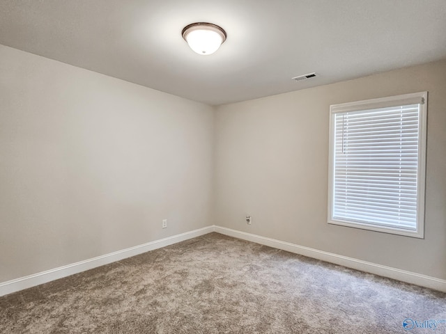 spare room featuring carpet flooring, visible vents, and baseboards