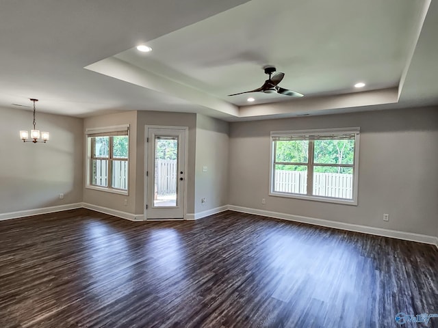unfurnished room with a wealth of natural light, baseboards, a raised ceiling, and dark wood finished floors