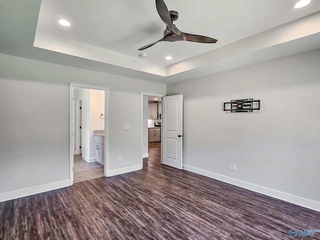 unfurnished bedroom with recessed lighting, a raised ceiling, baseboards, and wood finished floors