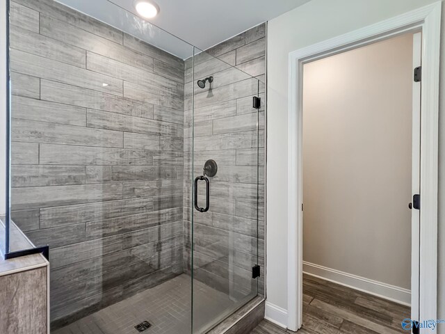bathroom featuring baseboards, wood finished floors, and a shower stall
