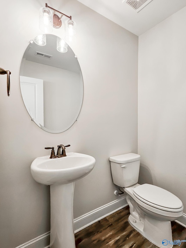 bathroom with wood finished floors, toilet, baseboards, and visible vents
