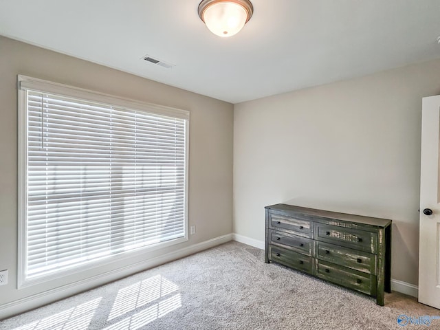 unfurnished bedroom with visible vents, carpet floors, multiple windows, and baseboards