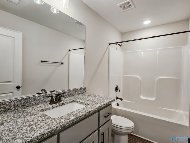 bathroom featuring visible vents, shower / washtub combination, toilet, wood finished floors, and vanity