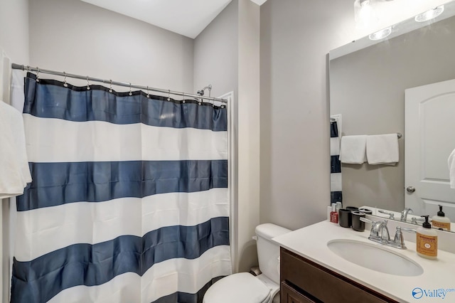 bathroom featuring vanity, curtained shower, and toilet