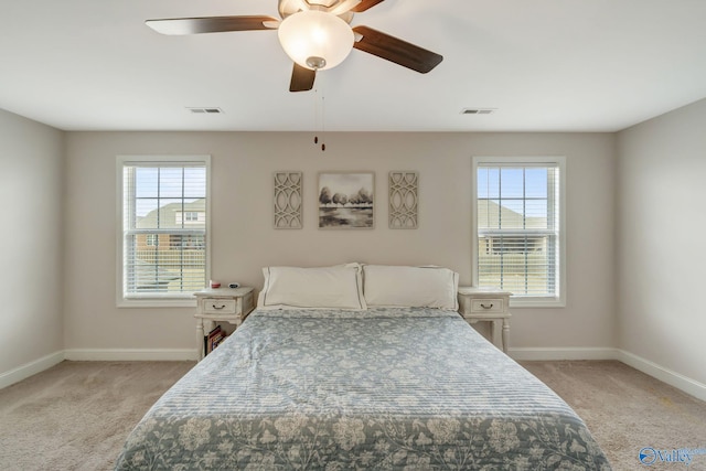 carpeted bedroom featuring multiple windows and ceiling fan