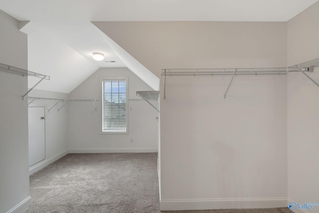 walk in closet with vaulted ceiling and light carpet