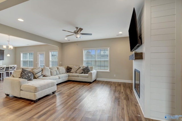 living room with hardwood / wood-style flooring, ceiling fan with notable chandelier, a large fireplace, and a wealth of natural light