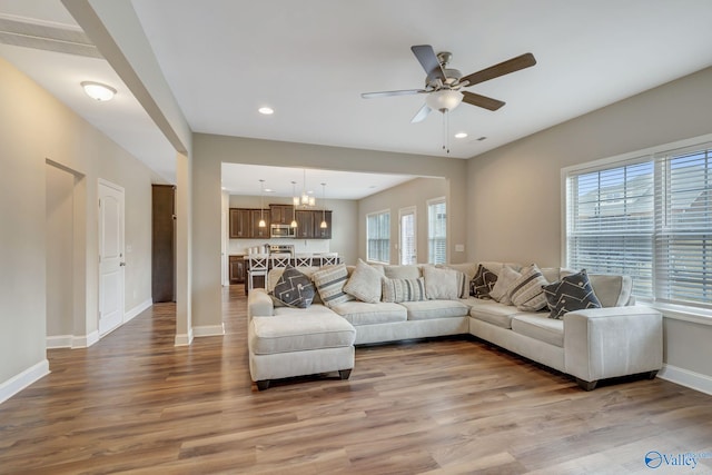 living room with ceiling fan with notable chandelier and wood-type flooring