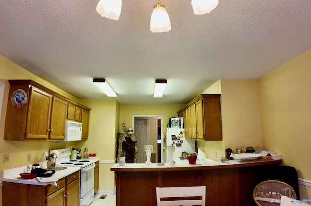 kitchen with a textured ceiling, white appliances, and kitchen peninsula