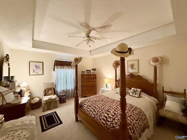 carpeted bedroom with ceiling fan, a raised ceiling, and a textured ceiling