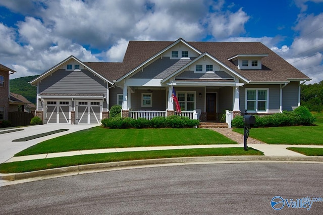 craftsman-style home with covered porch, driveway, a shingled roof, and a front yard