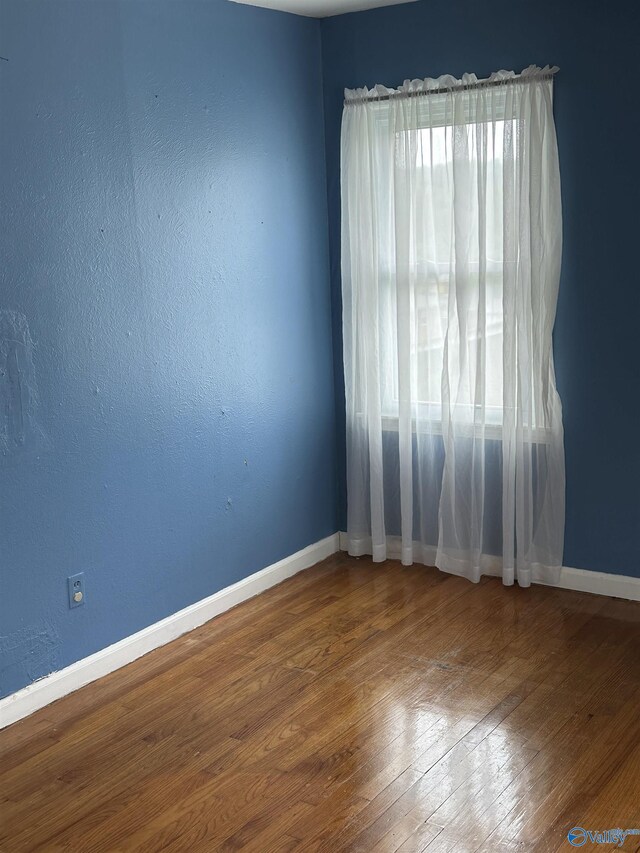 unfurnished room featuring wood-type flooring and baseboards