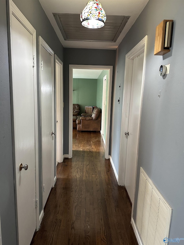 corridor featuring dark wood finished floors and baseboards