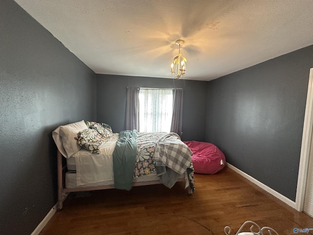 bedroom with baseboards, wood finished floors, and a chandelier