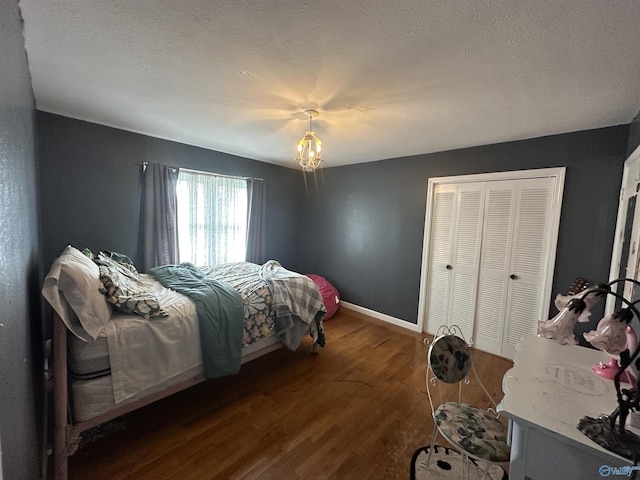 bedroom with wood finished floors, baseboards, a closet, a chandelier, and a textured ceiling