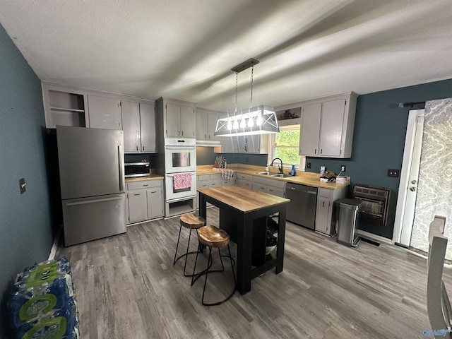 kitchen featuring stainless steel appliances, a sink, light wood-type flooring, and gray cabinets